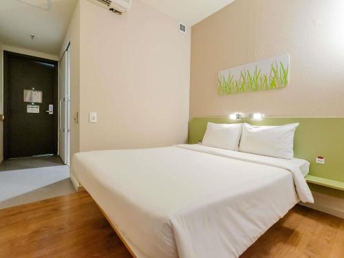 a large white bed in a room with a door at ibis budget Vitoria in Vitória