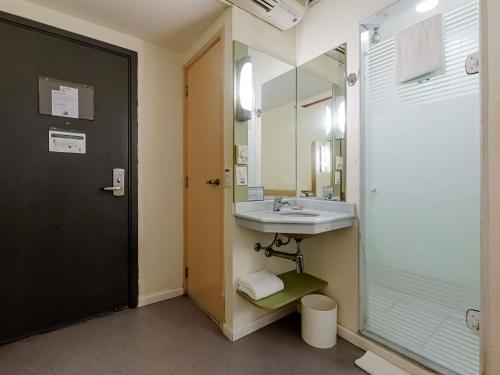 a bathroom with a sink and a glass shower at ibis budget Vitoria in Vitória