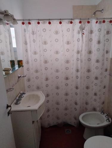 a bathroom with a sink and a toilet and a shower curtain at Ribera Apart in Necochea