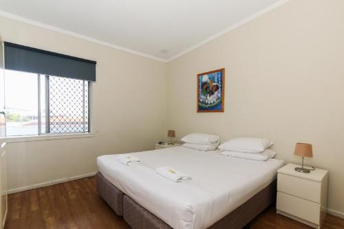 a bedroom with a large white bed and a window at Scarborough Apartments in Perth