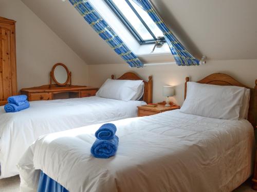 two beds in a bedroom with blue towels on them at Sunset Song in Arbuthnott