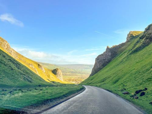 an empty road in the mountains with green hills at Eastry Cottage in Castleton