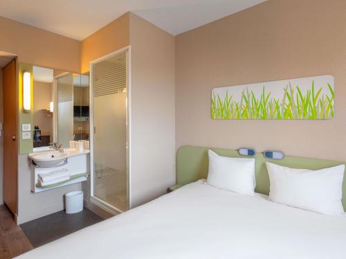 a bedroom with a large bed and a bathroom at Ibis Budget Manosque Cadarache in Manosque