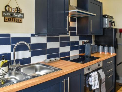 a kitchen with a sink and blue and white tiles at Ocean Breeze in Heysham