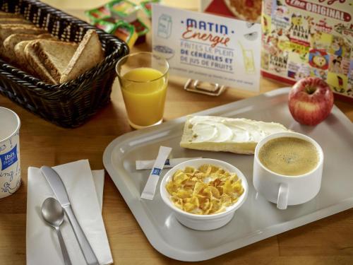 a breakfast tray with a bowl of cereal and a cup of coffee at ibis budget Rodez in Rodez