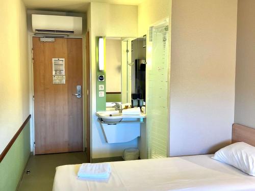 a bathroom with a bed and a sink and a mirror at Hotel Ibis Budget Cosne Sur Loire in Cosne Cours sur Loire