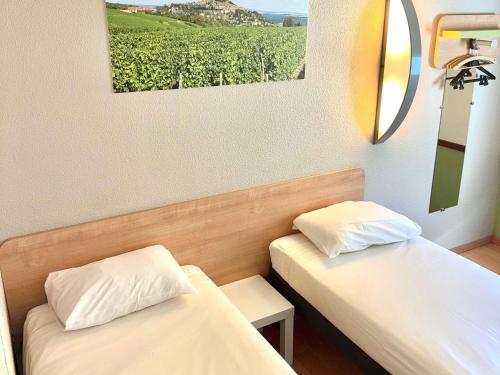 two beds in a room with a view of a vineyard at Hotel Ibis Budget Cosne Sur Loire in Cosne Cours sur Loire