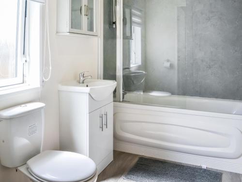 a white bathroom with a toilet and a tub and a sink at Carol Ann in Patrington