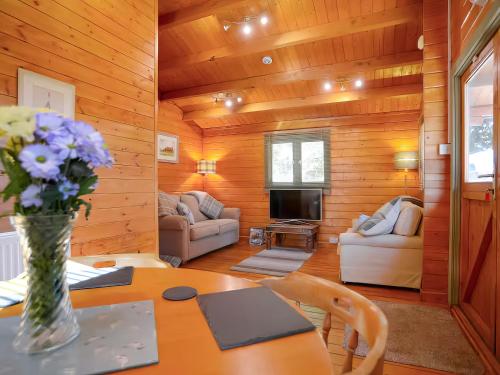 a living room with a table with a vase of flowers at Log Cabin in Guyhirn
