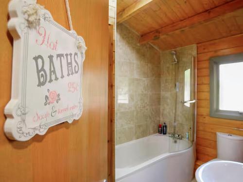 a bathroom with a tub and a toilet and a sink at Log Cabin in Guyhirn
