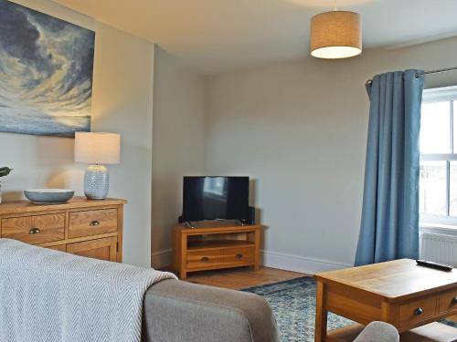 Una sala de estar con un sofá y un televisor. en High Tide - Uk50361, en Filey
