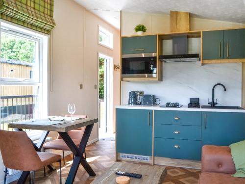 a kitchen with blue cabinets and a wooden table at Fairways Retreat 3 - Uk50248 in Cottingham