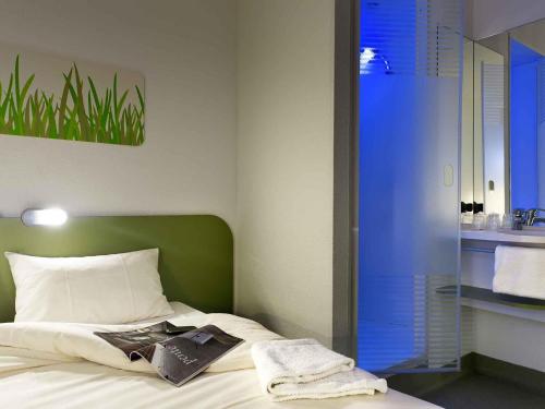 a bedroom with a bed and a bathroom with a sink at Ibis Budget Roanne Hôtel in Roanne
