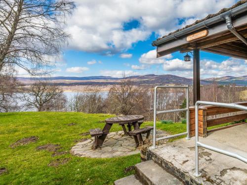a picnic table in a field with a view of a lake at Tamnavulin Lodge - Uk49121 in Feshiebridge