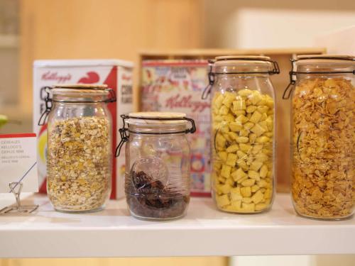 a shelf with four glass jars filled with nuts at ibis budget Saint-Quentin Centre Gare in Saint-Quentin