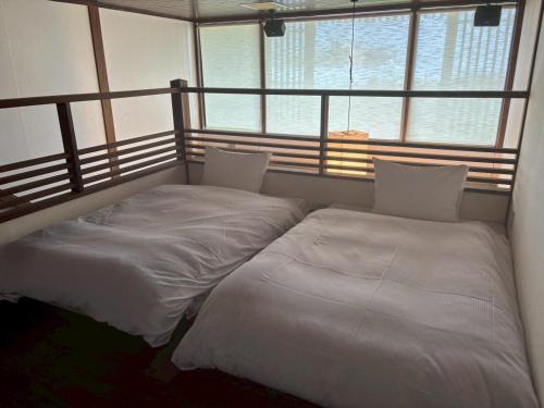 two beds sitting in a room with windows at 大同ガーデンホテル湯の山リゾート in Wada
