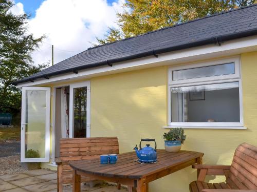 a picnic table in front of a yellow house at Brynllin Holiday Cottages - Dildre in Penuwch