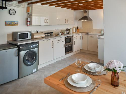 Una cocina con gabinetes blancos y una mesa de madera. en The Hilton, en Sheringham