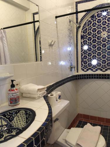a bathroom with a sink and a toilet and a mirror at Posada Colonial Beach Villas in San Juan