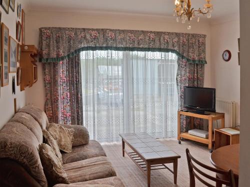 a living room with a couch and a television at Glan-Mor in Pwllheli