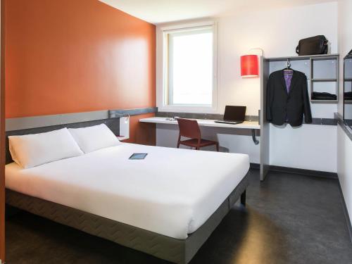 a bedroom with a bed and a desk with a computer at ibis budget Aéroport Lyon Saint Exupéry in Saint-Exupéry