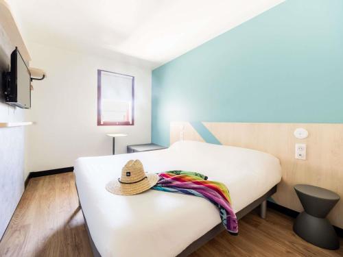 a bedroom with a bed with a hat on it at ibis budget Perpignan Centre Rénové en 2025 in Perpignan