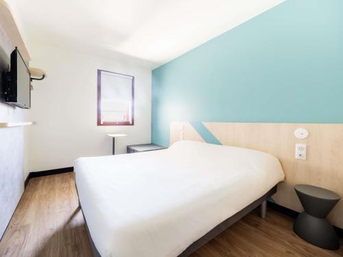 a bedroom with a white bed and a television at ibis budget Perpignan Centre Rénové en 2025 in Perpignan