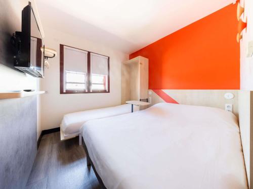 a hotel room with two beds and an orange wall at ibis budget Perpignan Centre Rénové en 2025 in Perpignan