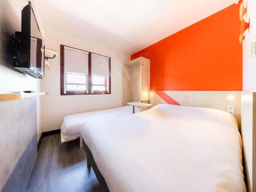 a hotel room with two beds and an orange wall at ibis budget Perpignan Centre Rénové en 2025 in Perpignan