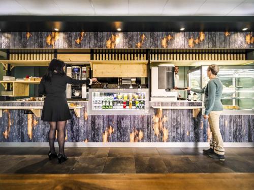 two women standing in a kitchen preparing food at ibis budget Bordeaux Aéroport in Mérignac
