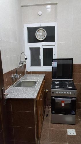 a small kitchen with a stove and a sink at Golden Seasons Furnished Apartment - 2 in Salalah