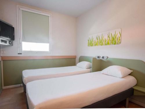 a room with two beds and a window at ibis budget Montauban Les Chaumes in Montauban