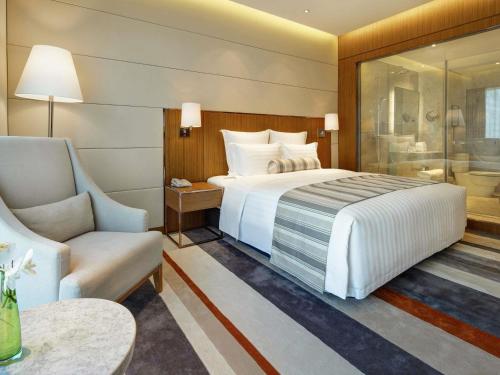a hotel room with a bed and a chair at Pullman Zhuhai in Zhuhai