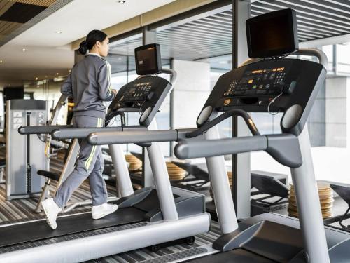 a woman walking on a treadmill in a gym at Pullman Zhuhai in Zhuhai