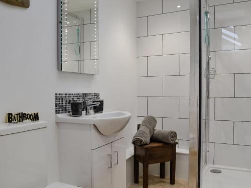 a white bathroom with a sink and a mirror at Y Gweithdy in Barmouth