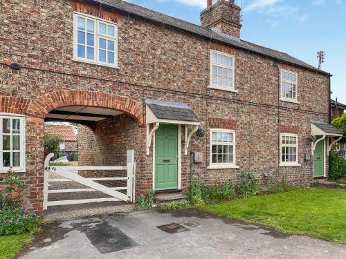a brick house with a green door and a gate at Rogue Cottage in Wheldrake