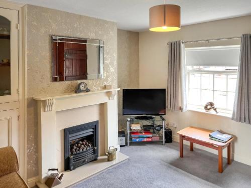 a living room with a fireplace and a tv at Rogue Cottage in Wheldrake