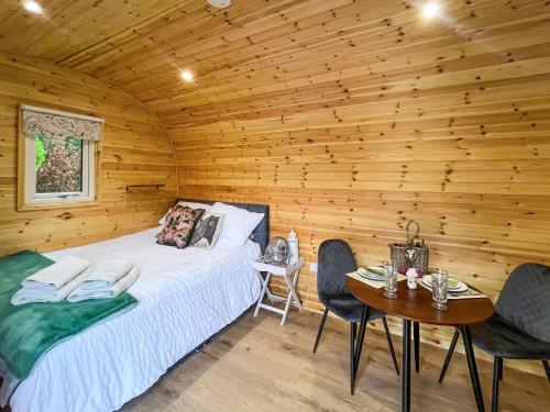 Cama en habitación de madera con mesa y sillas en Thula Lodge, en Chichester
