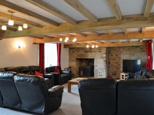 a living room with leather furniture and a fireplace at The Farm House in Wolsingham