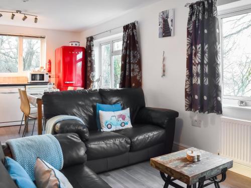a living room with a black leather couch and a table at Low Tide in Looe