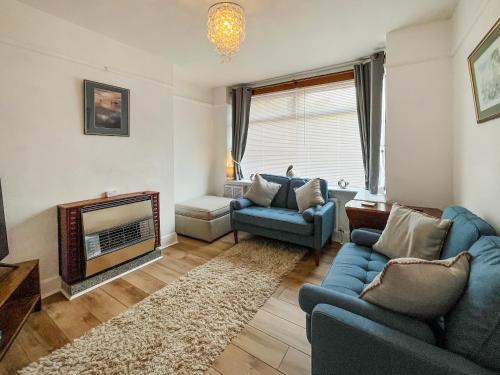 a living room with two blue couches and a fireplace at Blue Cherry Cottage in Penrith