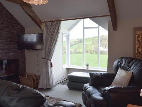 a living room with a couch and a large window at Upper Mill Barn in Nantgaredig