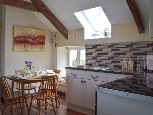 a kitchen with a table and a kitchen with a window at Upper Mill Barn in Nantgaredig