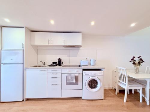 a white kitchen with a washing machine and a table at Lovely Estoril Apartment in Estoril
