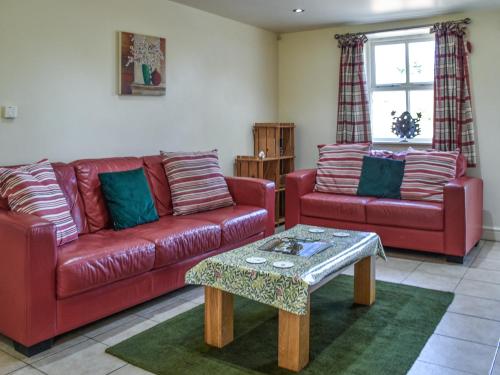 a living room with two red couches and a table at Lily Pad 1 - Uk49648 in Nassington