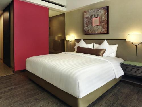 a bedroom with a large bed and a red wall at Mercure Bali Legian in Legian