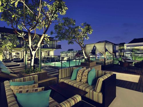 a patio with couches and a pool at night at Mercure Bali Legian in Legian
