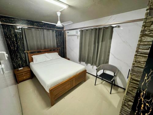 a small bedroom with a bed and a chair at A1 Homestay in Suva
