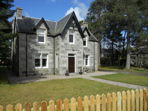 an old stone house with a wooden fence at Einich in Newtonmore
