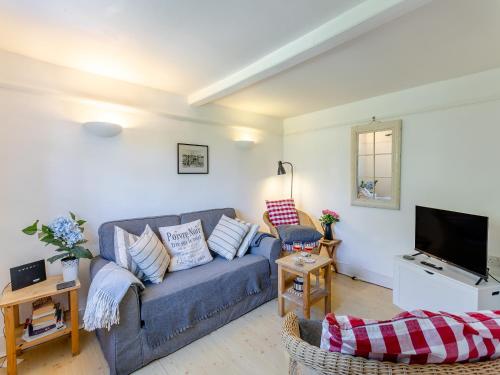a living room with a blue couch and a tv at Island Cottage in West Mersea